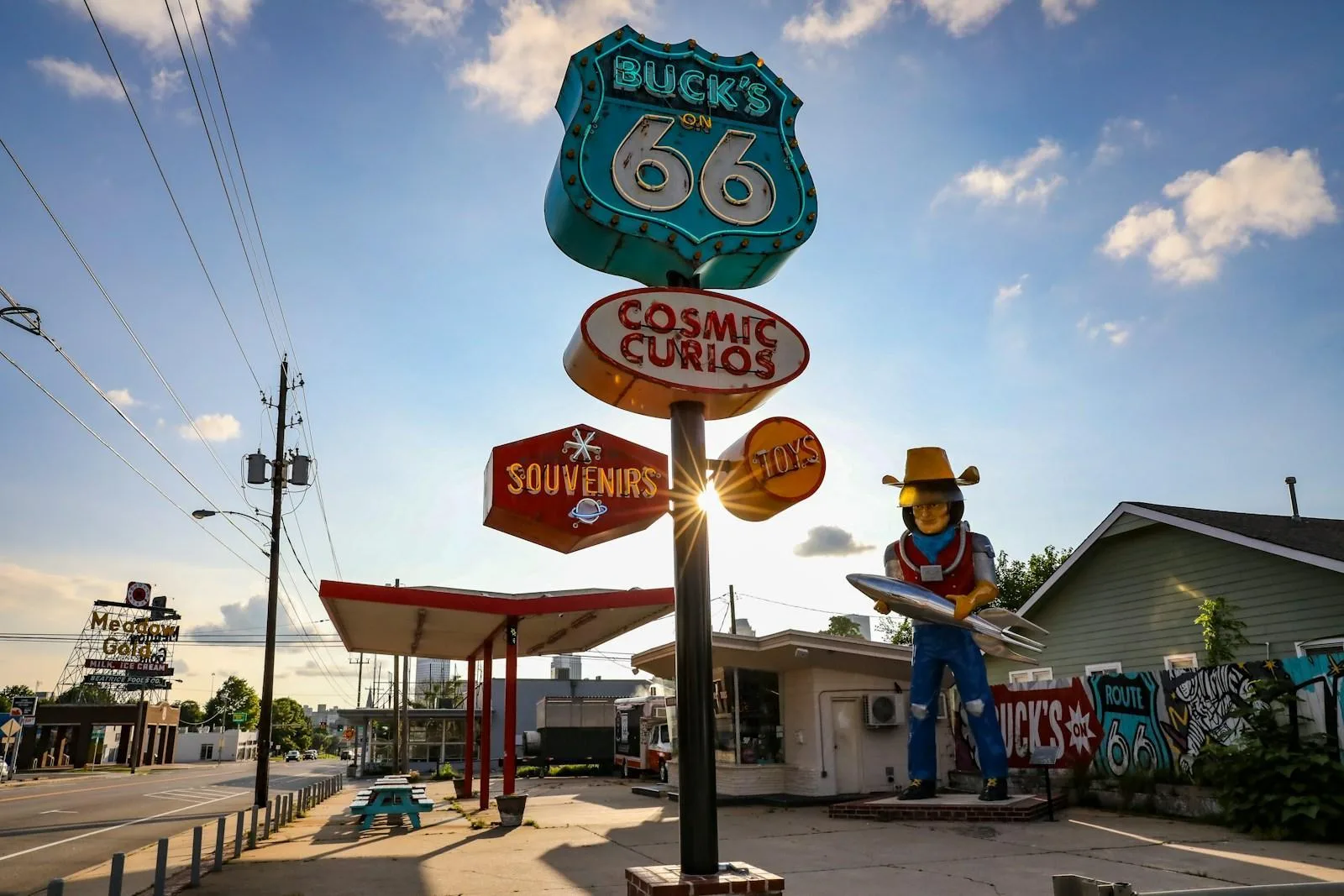 Route 66 - Iconic. Legendary. a statue of a cowboy holding a surfboard in front of a gas station
