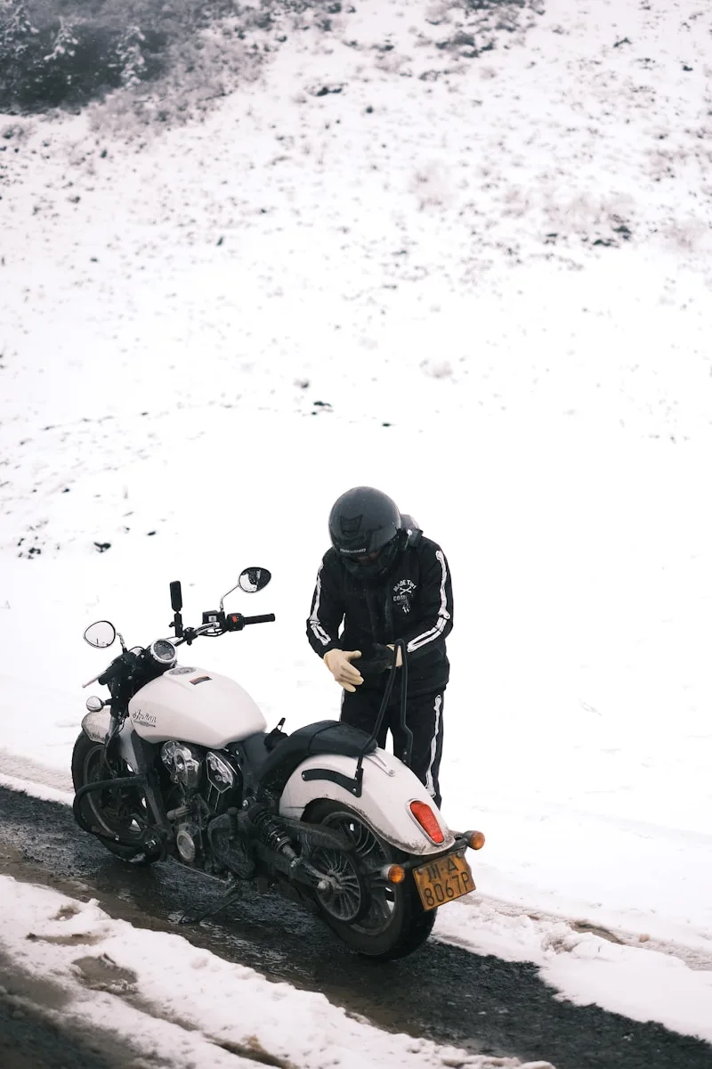 Motorcycle Riding Helmets a man standing next to a motorcycle on a snowy road