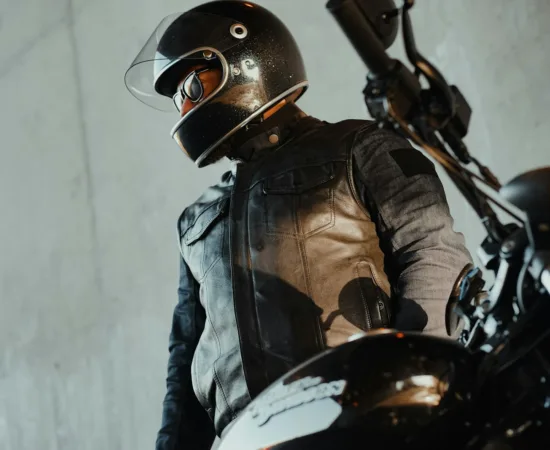 Motorcycle Riding Helmets a man in a leather jacket and helmet standing next to a motorcycle