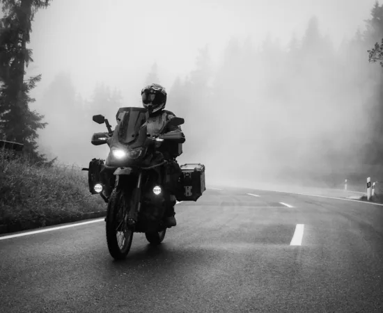 Motorcycle Riding Gloves a man riding a motorcycle down a foggy road