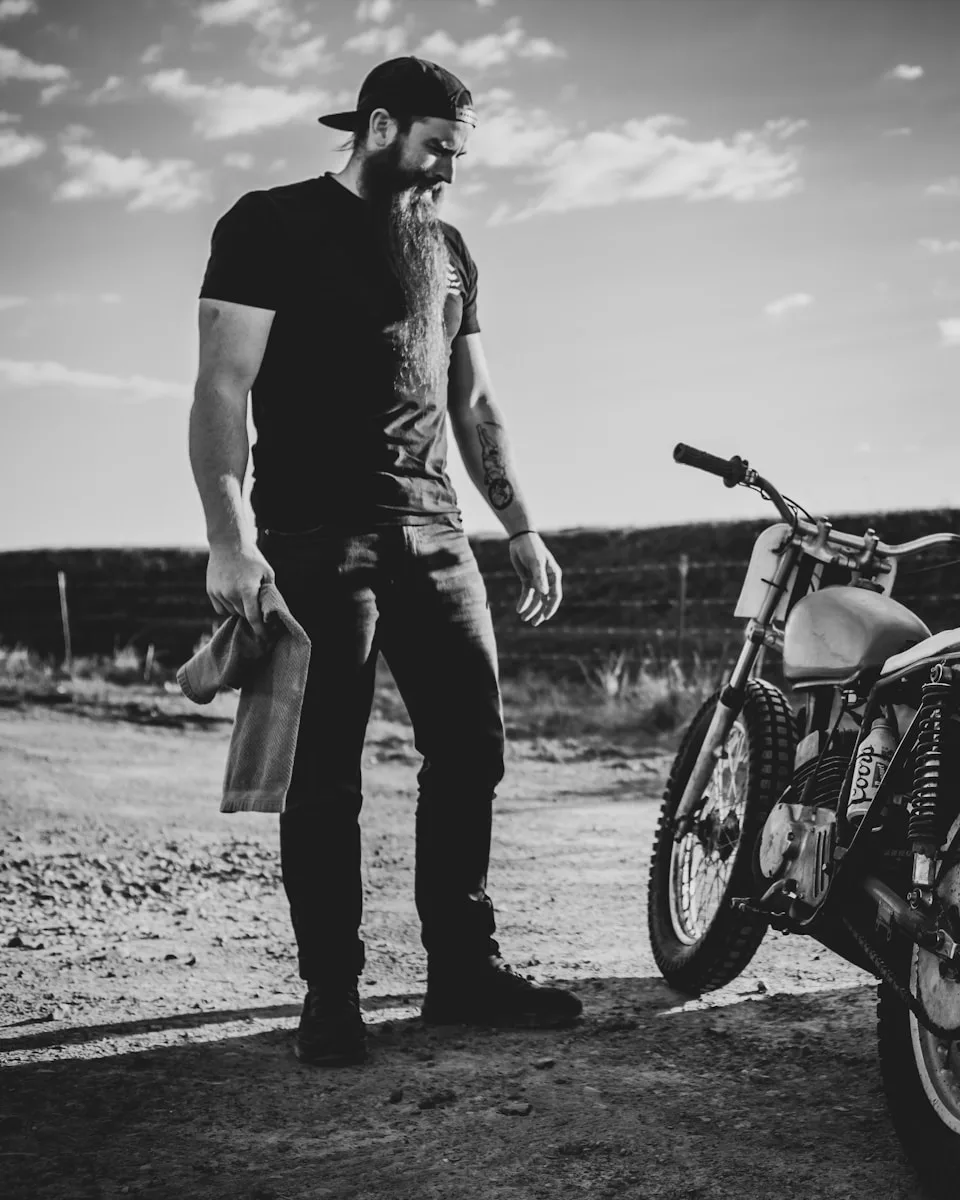 Products Hub man in black t-shirt and pants standing beside motorcycle
